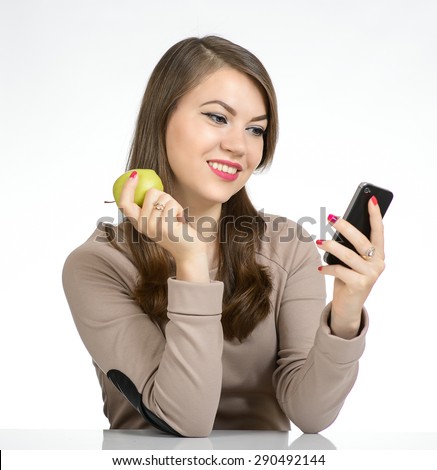 Portrait of a sweet young woman holding an apple and phone on a white background.