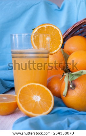 ripe orange fruits in the basket and a glass of freshly squeezed juice