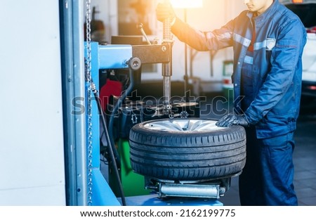 Auto mechanic loading automobile car wheel at tyre fitting machine during tire replacing auto service Stock fotó © 