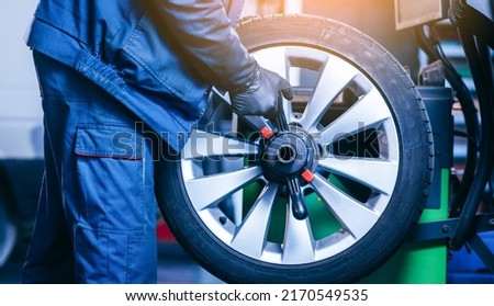 Auto mechanic uses tire balancing machine and turning tire	
 Stock fotó © 