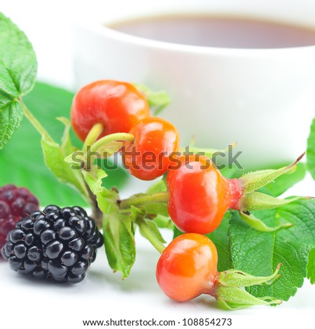 cup of tea, blackberry,raspberry and rosehip berries with leaves on white background