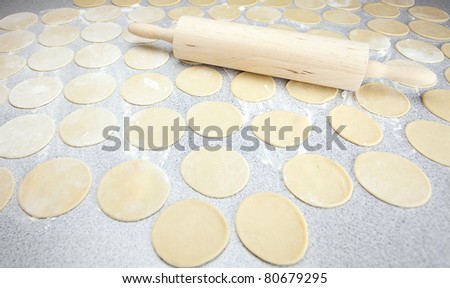 round shape of the dough and rolling pin with flour on the table