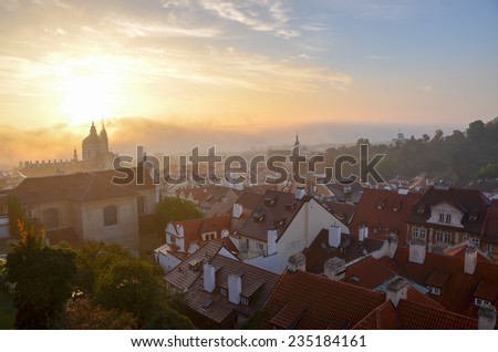 The sun rises above Prague\'s red rooftops on a foggy morning