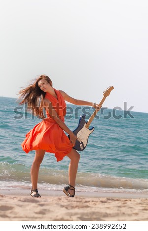 Girl playing the guitar. Beautiful girl with a guitar on the beach.