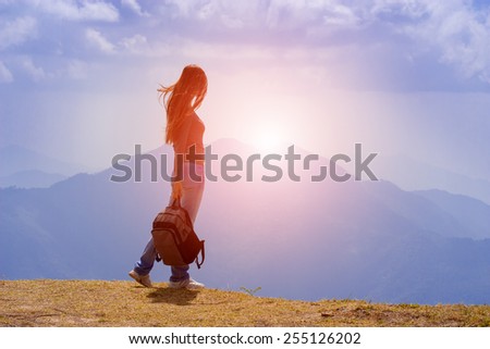 Woman Traveler with Backpack looking at mountain landscape on sky background