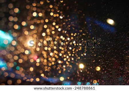Drops of rain on window at night with bokeh lights background