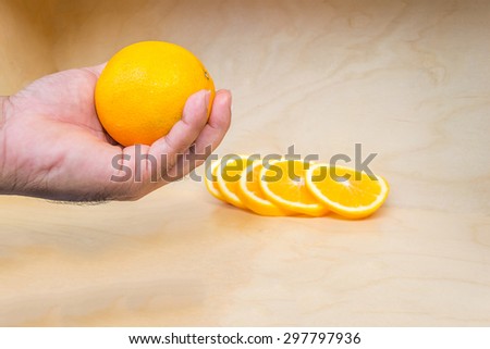 orange fruit in hand on wooden background. Focused on the orange in hand