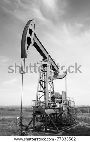 Oil and gas industry. Work of oil pump jack on a field. Environment damage. Black and white photo