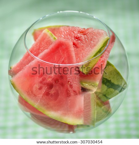 Watermelon slices in big  round  glass on checkered background