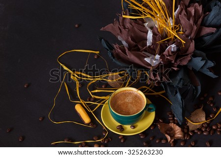 Cup of coffee with yellow paper flower,  yellow jelly  candy , coffee beans  on dark background