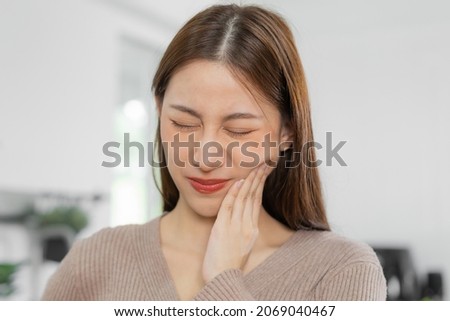 Closing eyes asian young woman touching cheek, face expression from toothache, tooth decay or sensitivity, Having tooth or teeth problem or inflammation, suffering from health. Sensitive teeth people Stock foto © 