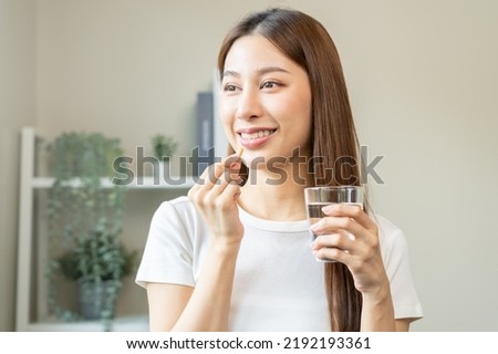 Dietary supplement, asian young woman, girl hand holding orange medical pill, take or eat vitamin C, D for treatment for skin, hair and nail strengthen with glass of pure water at home, healthcare. Foto stock © 