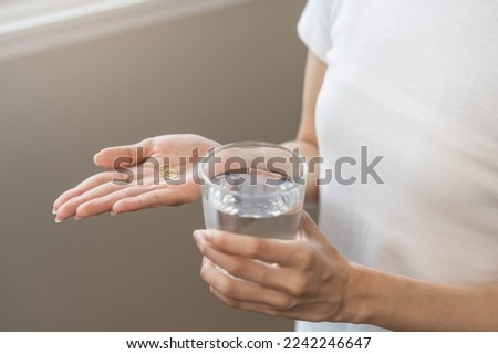 Dietary supplement, asian young woman hand holding fish oil or medical pill, take or eat vitamin C, D for treatment for skin, hair and nail strengthen with glass of pure water at home, healthcare. Foto stock © 
