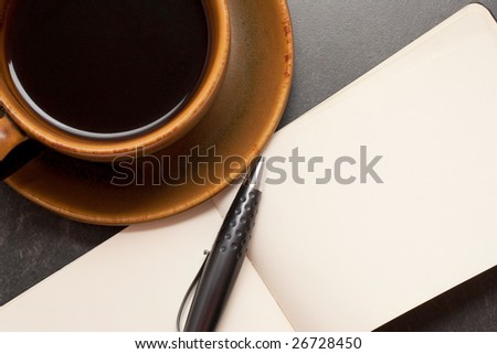 Hot cup of coffee with a blank notebook and pen ready to write down ideas
