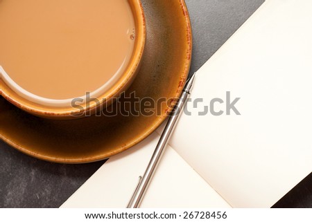 Hot cup of coffee with a blank notebook and pen ready to write down ideas