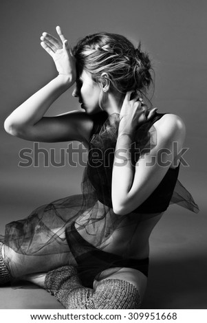A female dancer, posing in the black dance wear, at the grey background