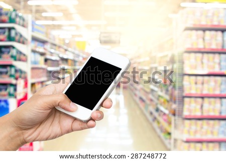 woman hand hold smart phone, tablet,cellphone on blur supermarket background