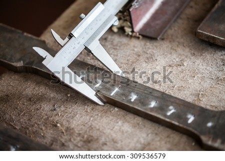 Worker measuring steel detail with Vernier Caliper