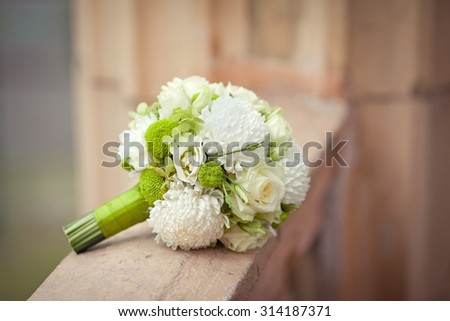 White and green bouquet on a stone parapet with rose, eustoma, chrysanthemum and dahlia. Horizontal closeup image