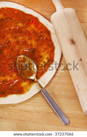 preparing a pizza pie on a wooden kitchen table