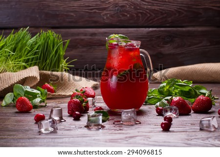 Glass jug of freshness lemonade with strawberries and cranberry.