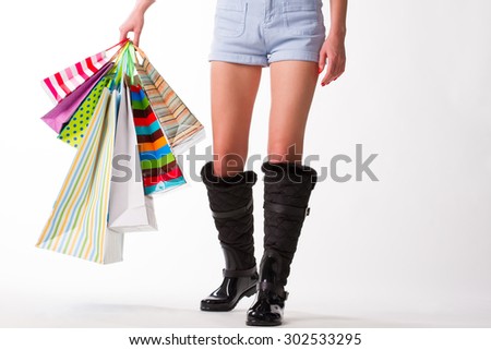 Girl goes with shopping bags in rubber boots.