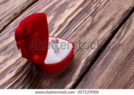 Ring for the proposal in a red box. Diamond ring on a wooden background.