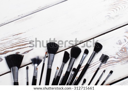 Black natural makeup brushes. Brushes on white wooden boards.