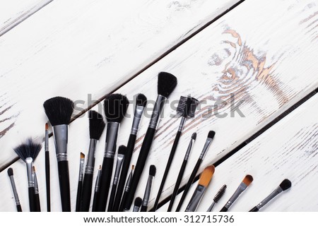 Black natural makeup brushes. Brushes on white wooden boards.