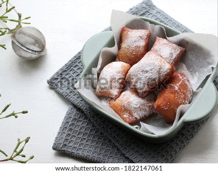 Beignet are square shaped pieces of dough, usually yeasted and raised doughs similiar to donut, deep fried and sprinkled with confectioners sugar. 
 Stockfoto © 
