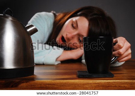Tired woman drinking coffee/tea and yawning.