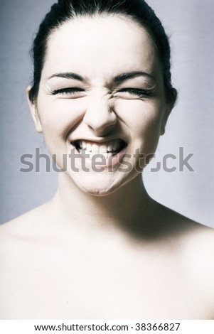 A young woman pulling a silly smile on a grey background.