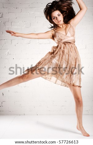 A young brunette model doing a crazy dance in a pretty dress.