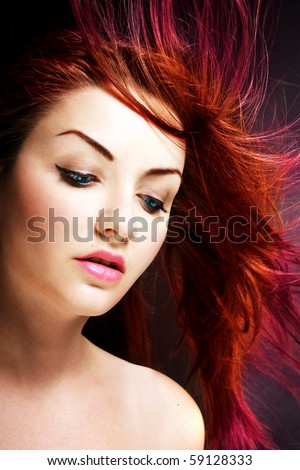 A young woman with her multicolored hair blowing in the wind.