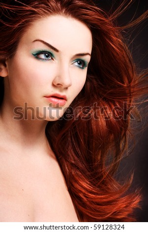 A beauty shot of a young blue eyed woman with her red hair flowing in the wind.