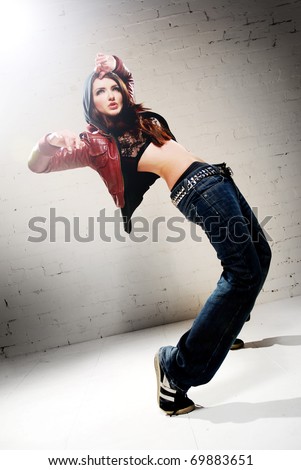 A ghetto styled girl dancing in front of brick wall