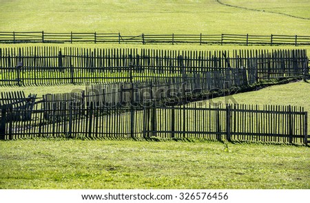 Old wooden fences on green meadow in autumn. Old fences.