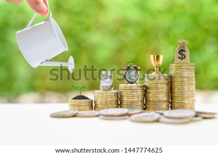 Long-term investment for sustainable growth, financial concept : Hand pours water from a watering can, small tree, saving jar, clock, trophy cup of success / winner prize reward, US dollar bag on coin Imagine de stoc © 