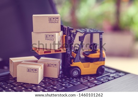 Logistics, supply chain and delivery service concept : Fork-lift truck moves a pallet with box carton. Boxes on a laptop computer, depicts wide spread of products around globe in ecommerce booming era Stockfoto © 