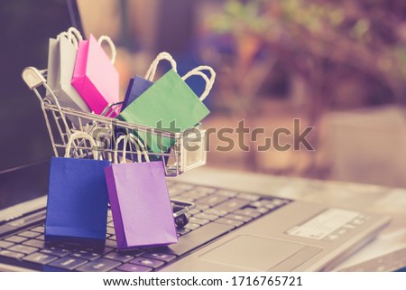 Online shopping  e-commerce and customer experience concept : Shopping bags and a shopping cart on a laptop keyboard, depicts consumers  buyers buy or purchase goods and service from home or office ストックフォト © 