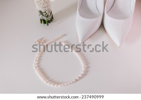 wedding pearl earrings and necklace close up with wedding shoes and bouquet background