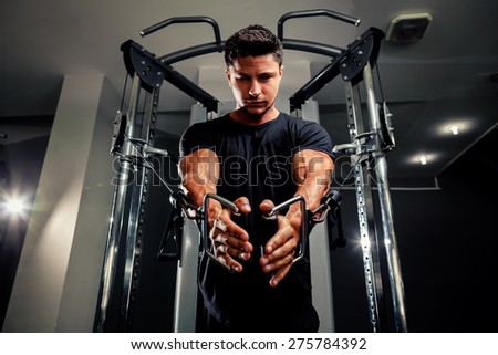 handsome bodybuilder works out  pushing up excercise in gym on trainer in black t shirt