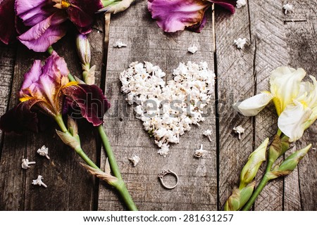 heart shape white lilac flowers and violet irises with proposal wedding ring on vintage wood table