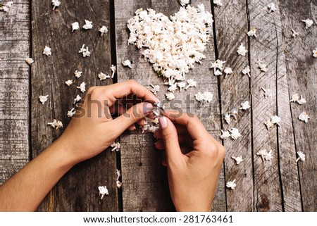 wedding proposal ring in hands with love heart shape white lilac flowers on vintage wood table background