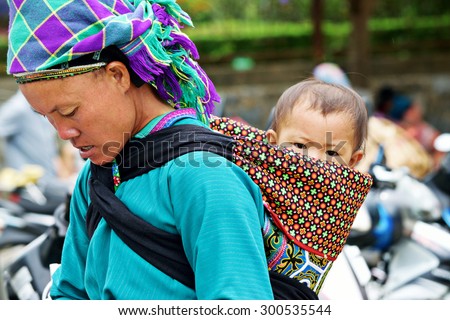 VIETNAM - BAC HA Market (LAO CAI) 2015 JUNE 21: A woman back carry a child go for shopping at the morning SUNDAY Market in north of Vietnam.