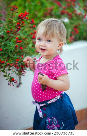 Cute little girl in a pink blouse costs about flower