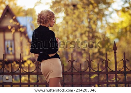 Portrait in profile of a sensual kinky girl in the black coat in the autumn on the background of the house