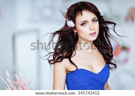 Portrait of a gentle sensual beautiful young girl brunette in blue dress with flowing hair, close up