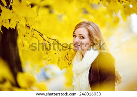 Very beautiful redhead girl with freckles on the background of yellow autumn leaves