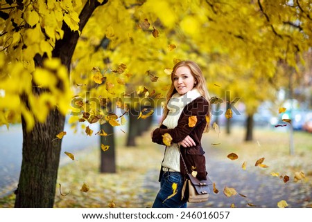 Very beautiful redhead girl with freckles in the background flying yellow autumn leaves